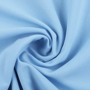 Dettaglio macro del tessuto dell'abito azzurro con una trama fine e pieghe a spirale