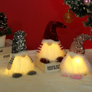 Nahaufnahme von drei leuchtenden Weihnachtswichteln mit bunten Paillettenhüten als Deko