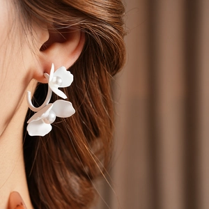 Detail of white flower pearl earring on model with C-shaped design and elegant finish