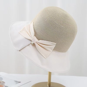 Women's Japanese straw hat with wide white brim and large bow on a gold display stand