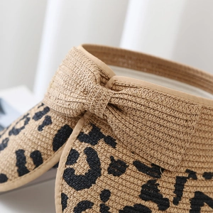 Close-up of leopard print straw sun hat showing woven texture and decorative bow detail