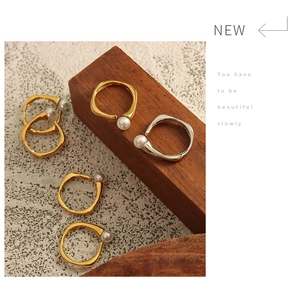 Close-up of gold and silver irregular open rings with elegant faux pearl accents