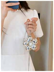 Detail of silver metallic flower mini bag with large pearl and chain strap held by hand