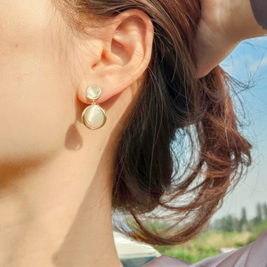 Detail view of double circle earrings with cat eye stones in a gold metal frame on model