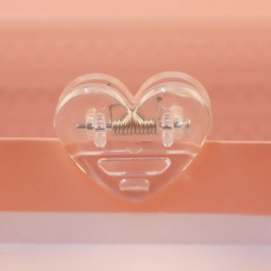 Macro view of transparent heart-shaped plastic paper clip with metal spring detail