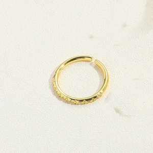 Close-up of gold-plated minimalist ring featuring intricate textured metal patterns