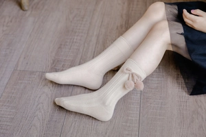 Detail of baby knee-high socks with pom-poms, cherries, and vertical rib texture