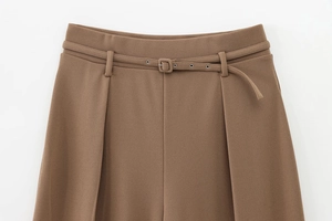 Detail view of brown high-waisted wide-leg trousers with matching fabric belt and metal eyelets