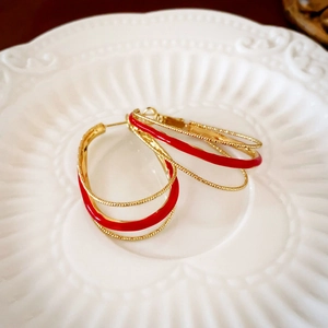 Close-up of vintage gold multi-layer hoop earrings with vibrant red enamel on white plate