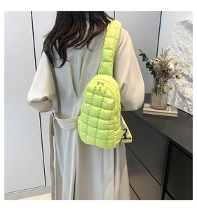 Detail of neon green quilted crossbody bag with adjustable strap and buckle on model
