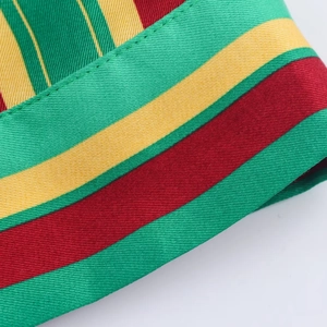 Detail shot of striped woven fabric featuring red, green, and yellow twill texture and stitching