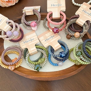 Close-up of colorful spiral hair ties with star and heart resin charms in a wooden tray