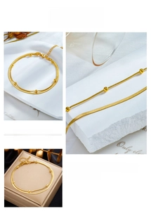 Macro detail of gold-plated double-layered chain anklet with round beads and lobster clasp