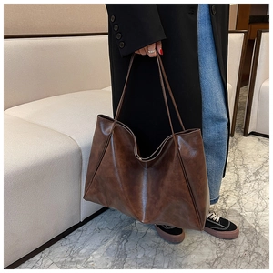 Detail of vintage dark brown tote bag in oily wax leather shown with a shoulder strap