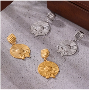 Detailed view of gold and silver sun hat earrings with bow and woven texture