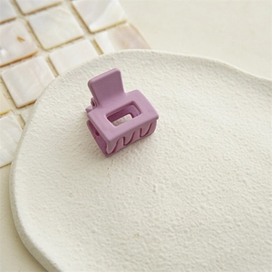 Close-up of a matte mauve square hair claw clip on a white decorative plate