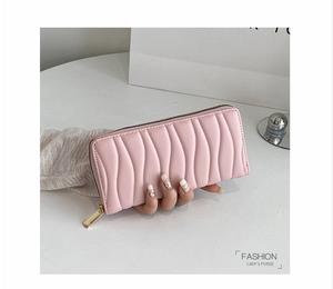 Detailed close-up of a long pink PU leather wallet with wavy quilted pattern and gold zipper