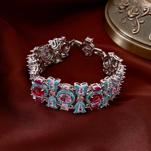 Dettaglio di bracciale vintage argentato con pietre ovali rosse e rosa su seta rossa