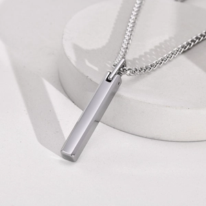 Close-up of a sleek silver rectangle pendant necklace on a premium textured surface