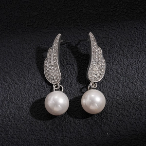 Detail shot of silver wing pendant earrings with sparkling rhinestones and round white pearls