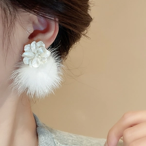 Détail de boucle d'oreille fleur blanche avec pompon doux sur un mannequin pour l'automne