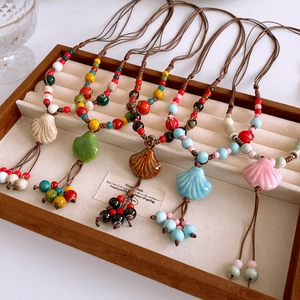 Detail of colorful ceramic shell pendants on bohemian woven necklaces in a jewelry tray