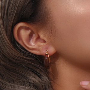 Detail shot of amber resin teardrop earrings with gold hooks on a fashion model