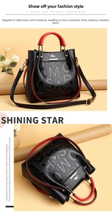 Detail of black pebbled leather tote with red trim, golden kangaroo logo and hardware