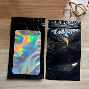 Detailed view of black resealable pouch with holographic laser sticker on wood background
