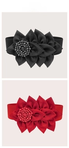 Close-up of elastic waist belts featuring large fabric flowers and beaded centers
