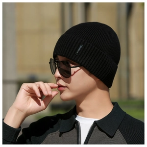 Detail of black ribbed knit beanie with small woven label and warm folded cuff