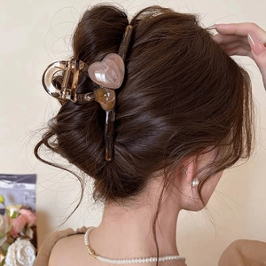 Eleganter bernsteinfarbener XL-Haarclip mit rosa Marmor-Herz-Detail am Haarknoten