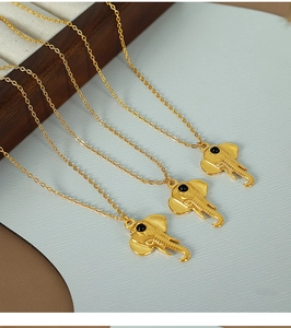 Detailed view of three minimalist golden elephant pendant necklaces on a white display
