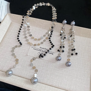 Detail of Y-shaped tassel necklace and earrings set with grey pearls and black beads