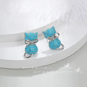Macro detail of cat-shaped silver earrings with blue pavé zircons and bow accent