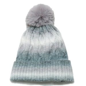 Detail showing cable knit texture and faux fur pom-pom on the ombre winter beanie hat