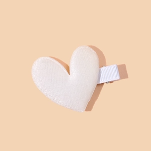 Detail shot of a plush white velvet heart hair clip with grosgrain ribbon wrap