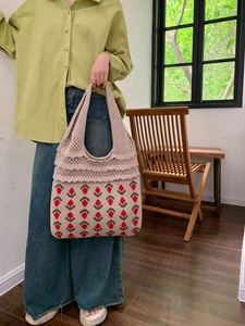 Close-up of handmade knit tote bag with red strawberry floral patterns and crochet straps