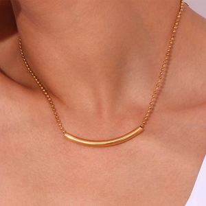Makroaufnahme einer minimalistischen 18K vergoldeten Kugelkette mit gebogenem Rohr-Anhänger