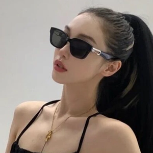 Detail view of black square sunglasses featuring a golden U-shaped metal hinge on the temple
