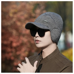 Detail of grey knitted winter hat with visor and earflaps, showing warm fleece lining