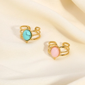 Detail of adjustable triple-layer gold rings with turquoise and pink stones on fabric