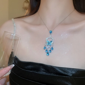 Detail of silver necklace with blue butterfly pendant and tassels worn by a model