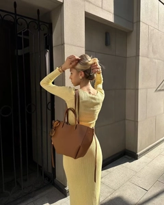 Détail d'une robe en maille côtelée jaune à manches longues avec un grand sac cabas en cuir