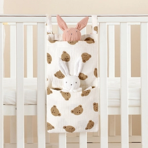 Cotton baby crib organizer with bear prints and two pockets hanging on a white wooden crib