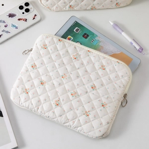 Close-up of white quilted floral cotton sleeve for 11 inch tablet on workspace desk