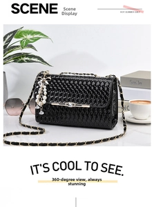 Detail of black woven shoulder bag with gold chain and pearl bow pendant decoration