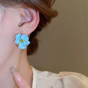 French vintage flower stud earrings with blue petals and yellow diamond center on model