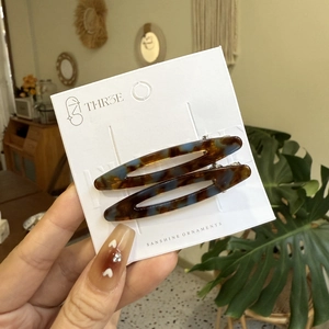 Détail de deux barrettes à cheveux à motif écaille de tortue en marron et bleu