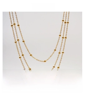 Detail of a triple-layered gold titanium steel necklace with polished bead accents